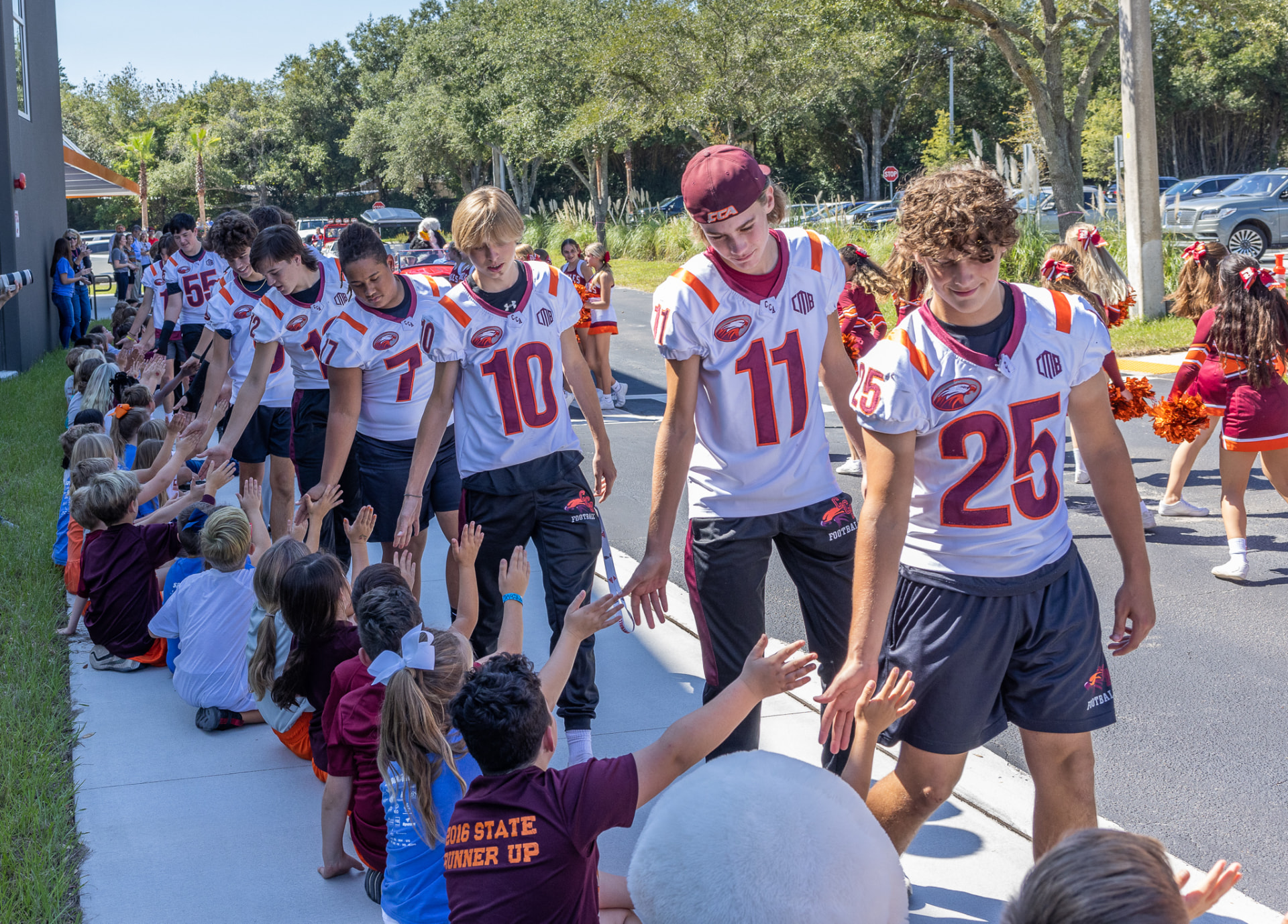 CCA football players high-fiving preschool children on campus